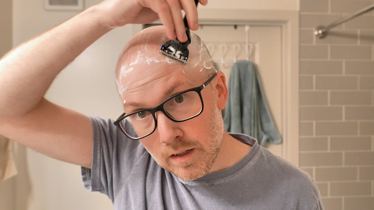 Shawn shaving a small section near the top of his head with a cartridge razor