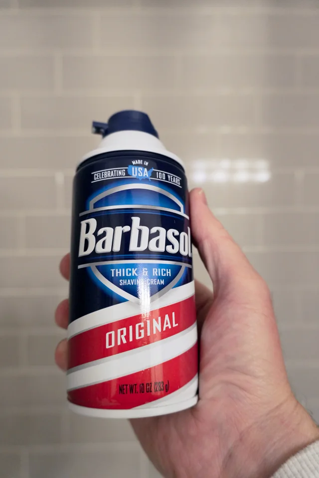 Holding a 10-ounce can of Barbasol Original shaving cream