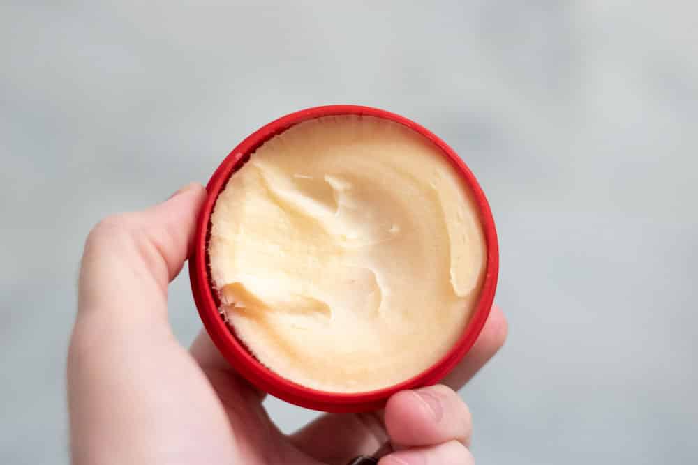 hand holding up cella shaving cream showing consistency