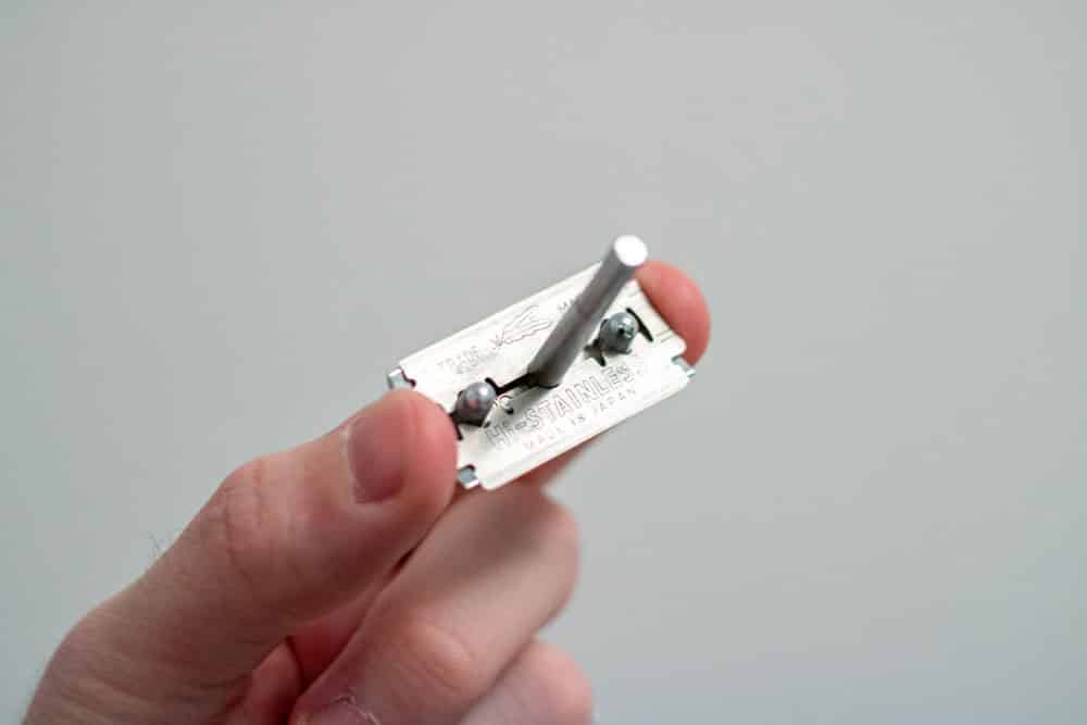hand holding razor cap with feather razor blade loaded