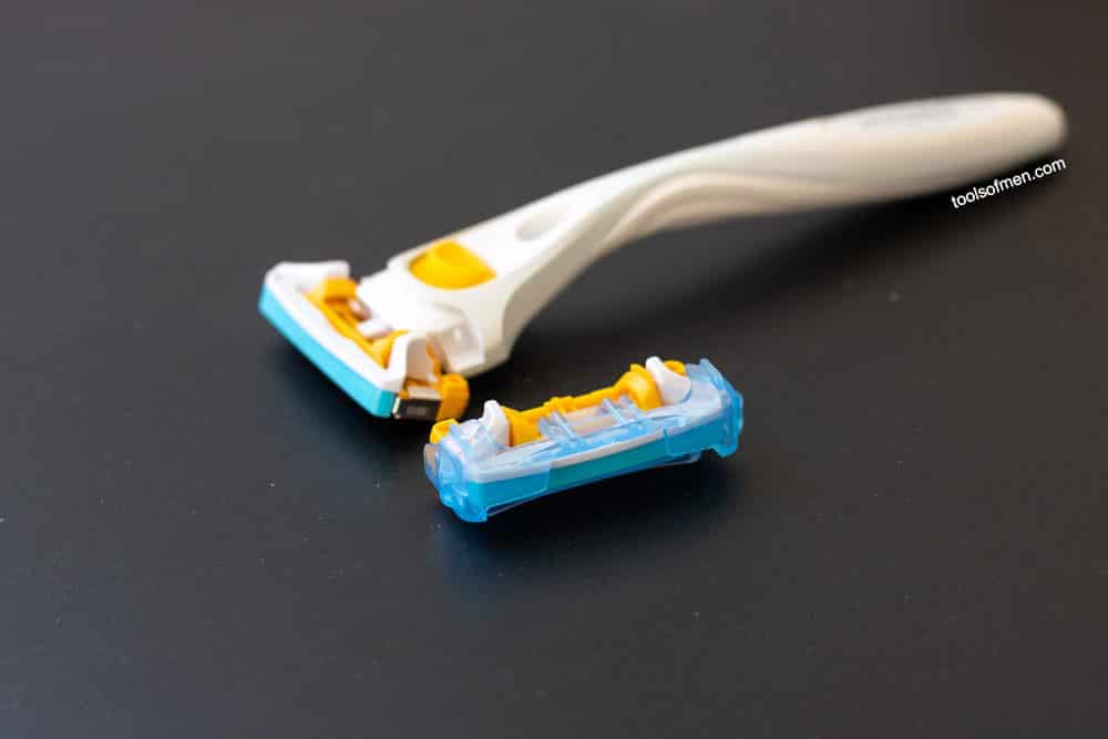 schick stubble eraser on black mat next to replacement cartridge