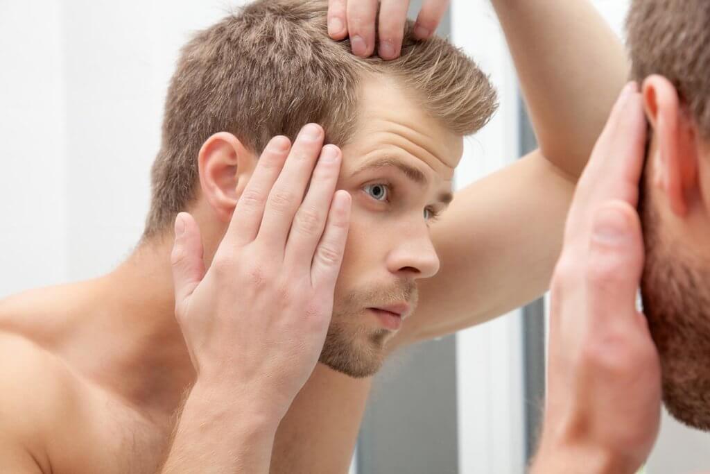 man inspecting hair for signs of hair loss