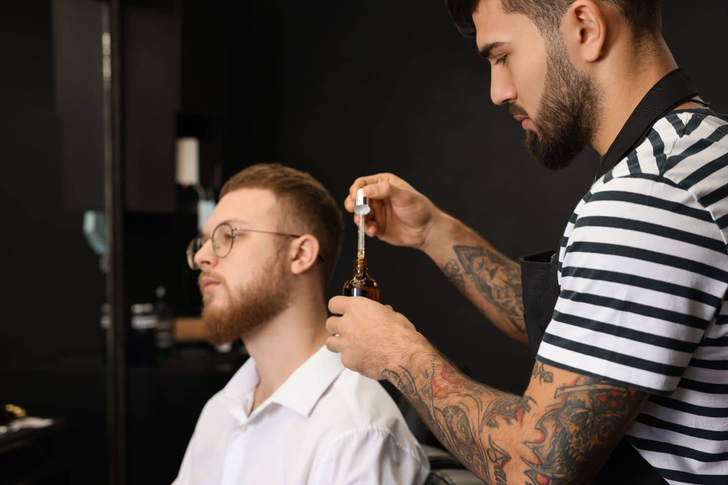 barber applying beard oil to client