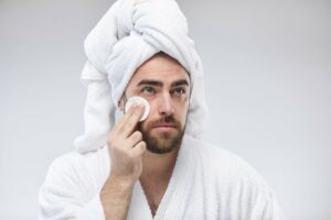 man applying a face toner with a cotton pad