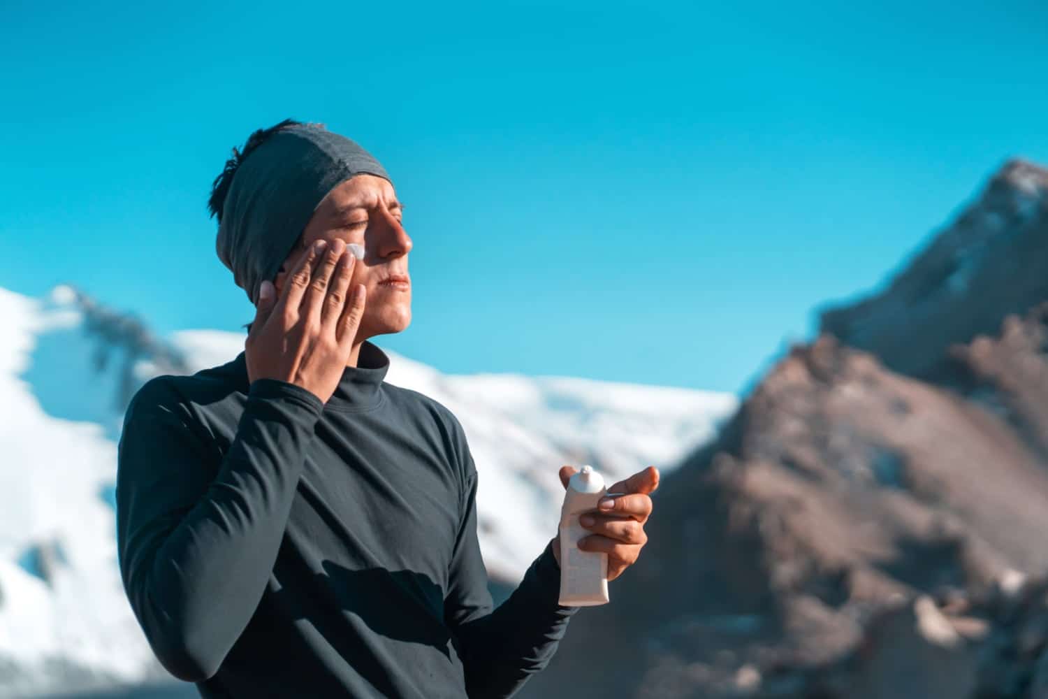 man applying sunscreen while hiking outdoors