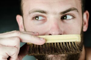 man holding a beard brush up to his mouth