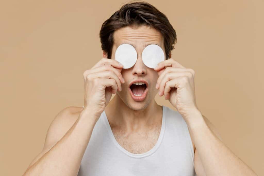 man holding two cotton pads on his eyes