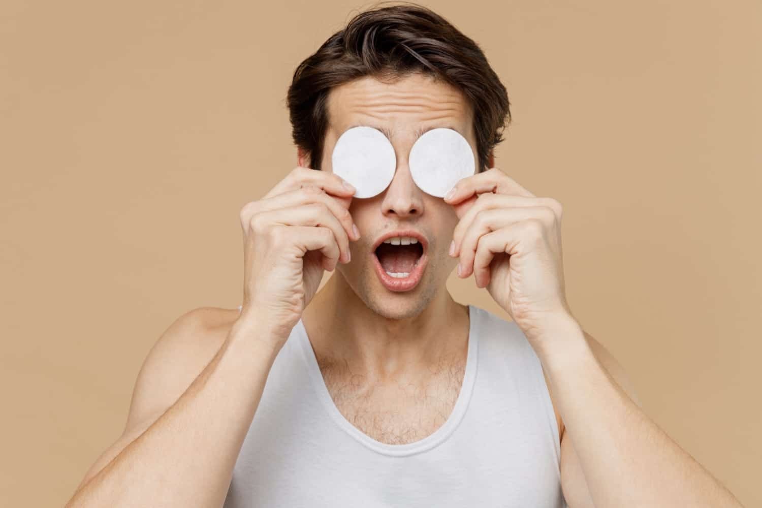 man holding two cotton pads on his eyes
