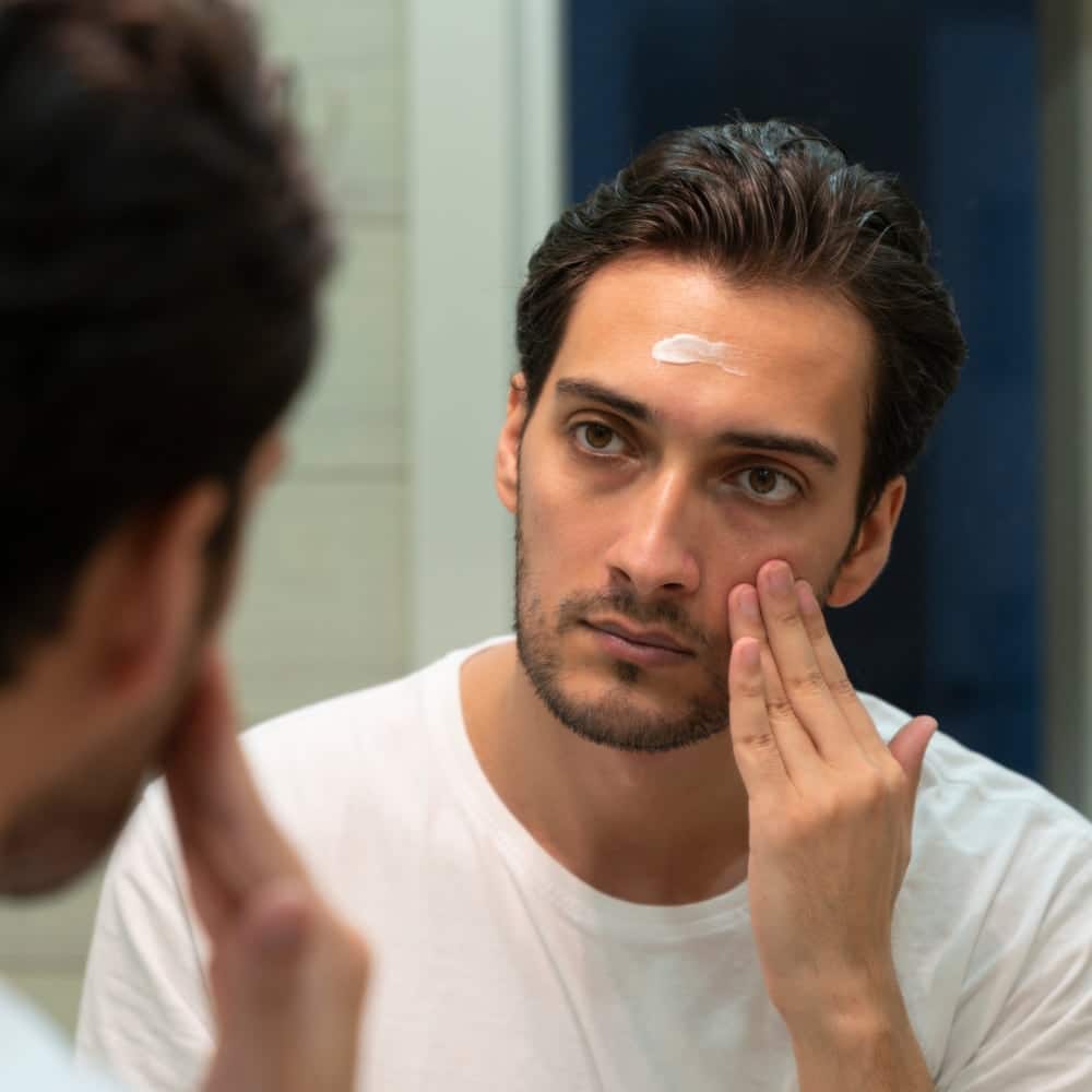 man looking into mirror with skincare product on head