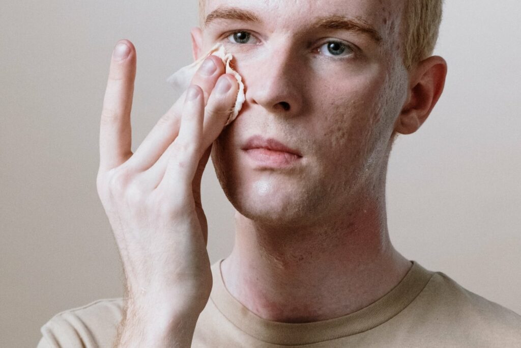 man rubbing a cotton pad on his face