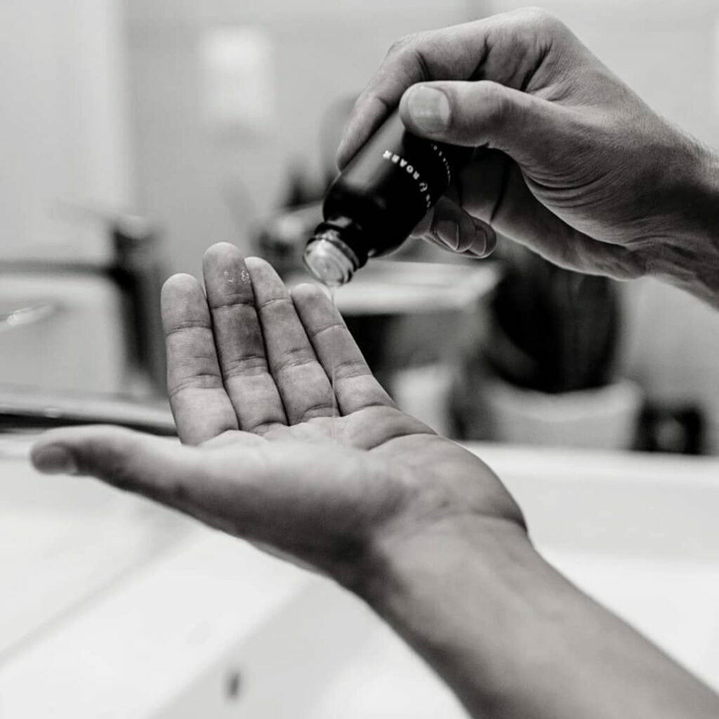 a man pouring fulton and roark beard oil into palm of hand