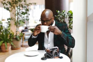 bald man sipping from white ceramic cup
