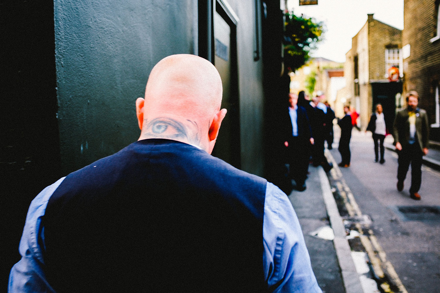 bald man wearing blue suit walking on sidewalk
