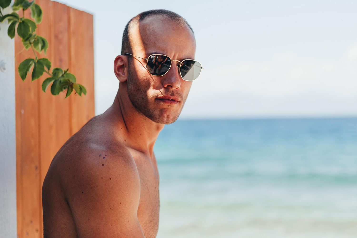 bald man wearing sunglasses sitting by the beach
