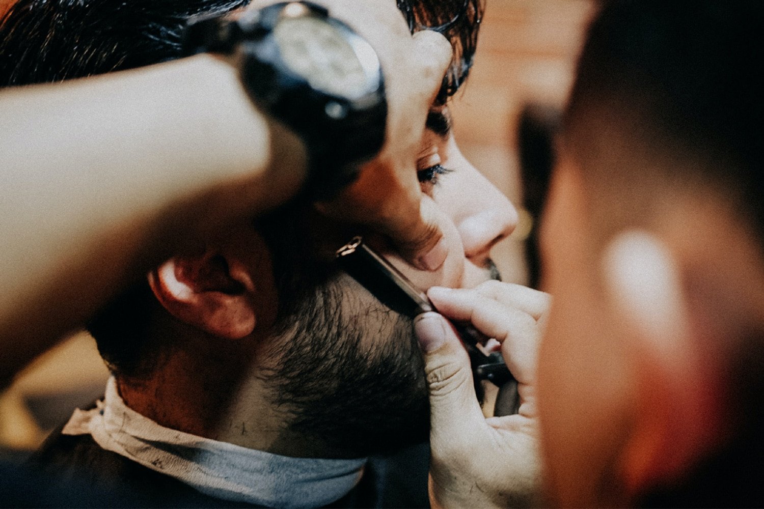 barber using a straight razor on a beard