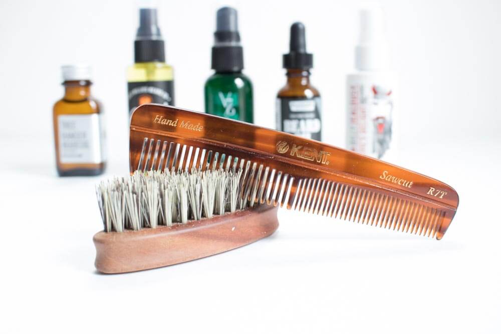 beard comb and brush in foreground with beard oil in background