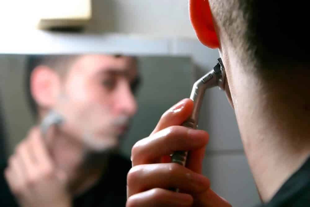 behind the head view of a man shaving with razor