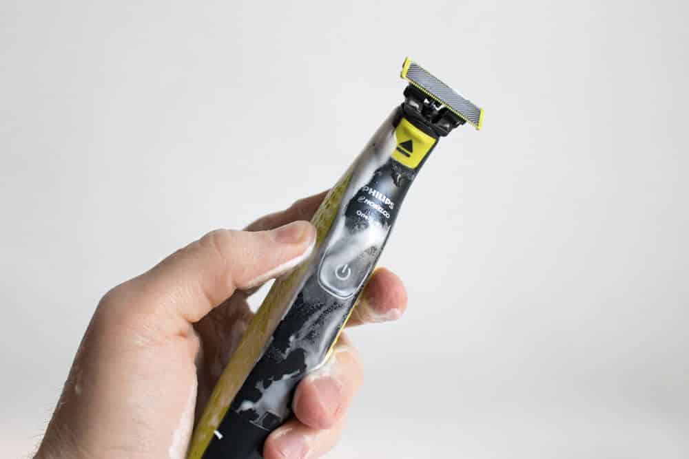 hand holding the oneblade trimmer while coated in shaving cream