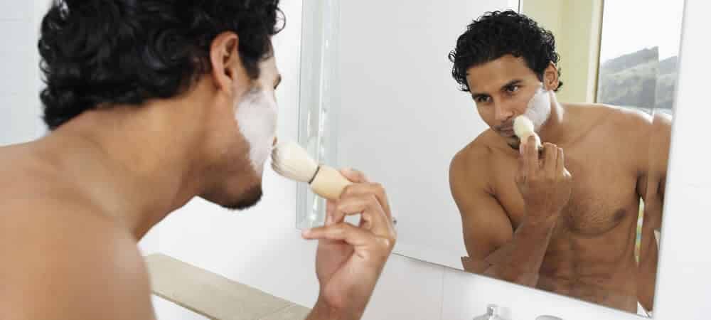 man applying a thick shaving cream with a shaving brush