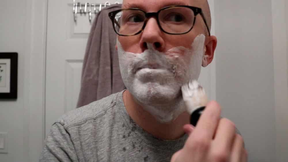 man applying shaving cream to face with a brush