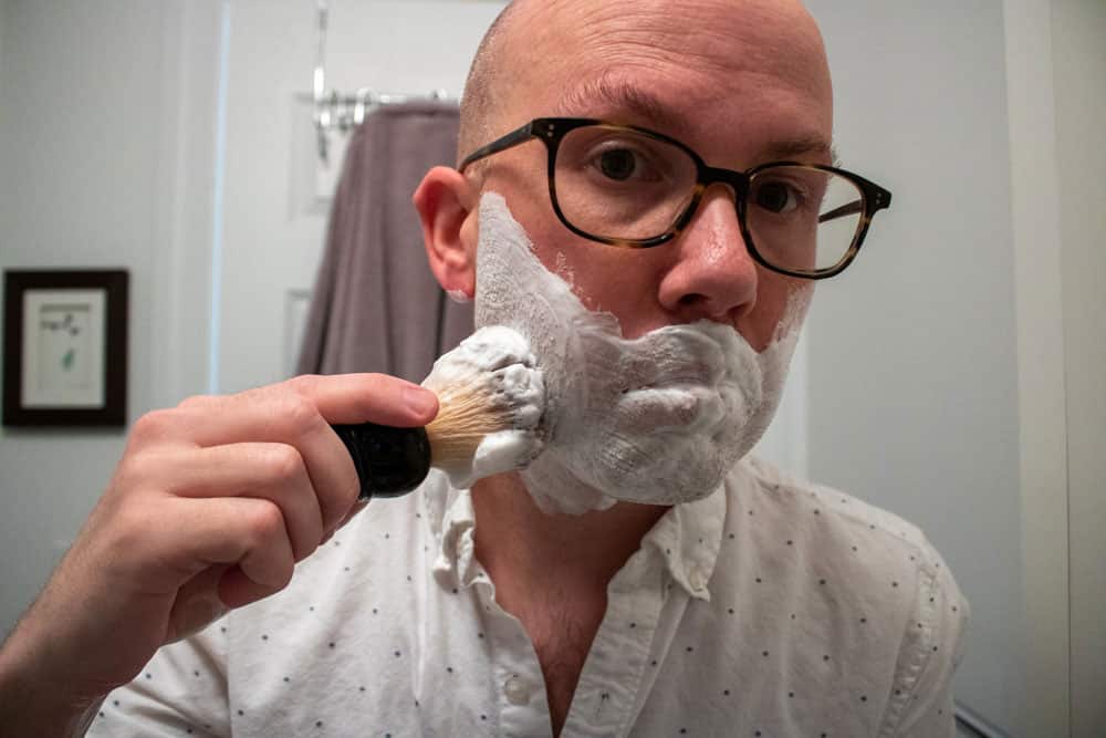 man applying shaving cream to face with a shaving brush