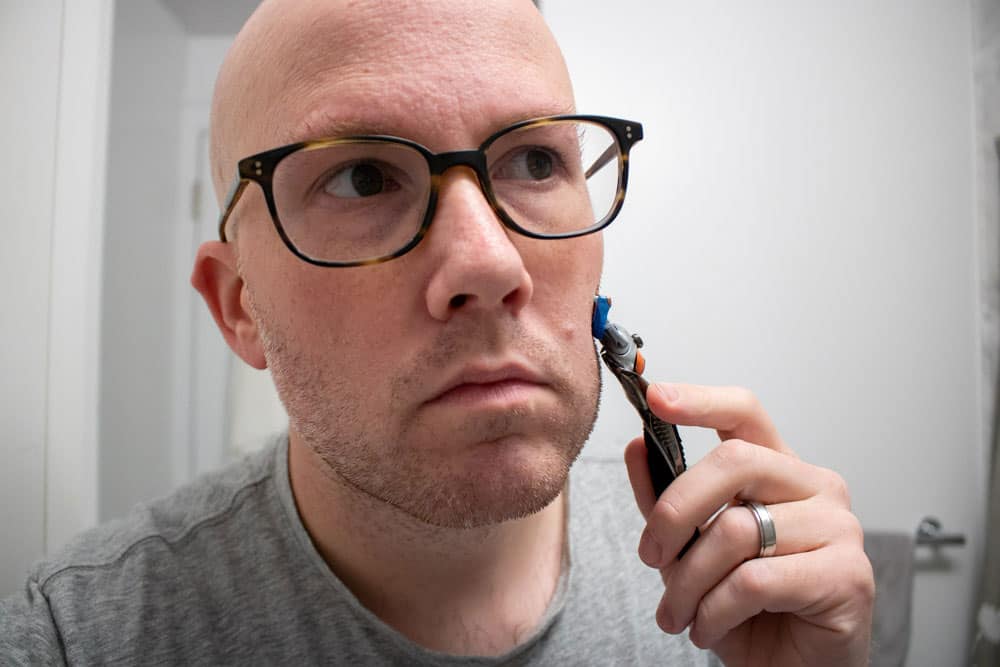 man demonstrating a cartridge razor pressed down too hard on cheek