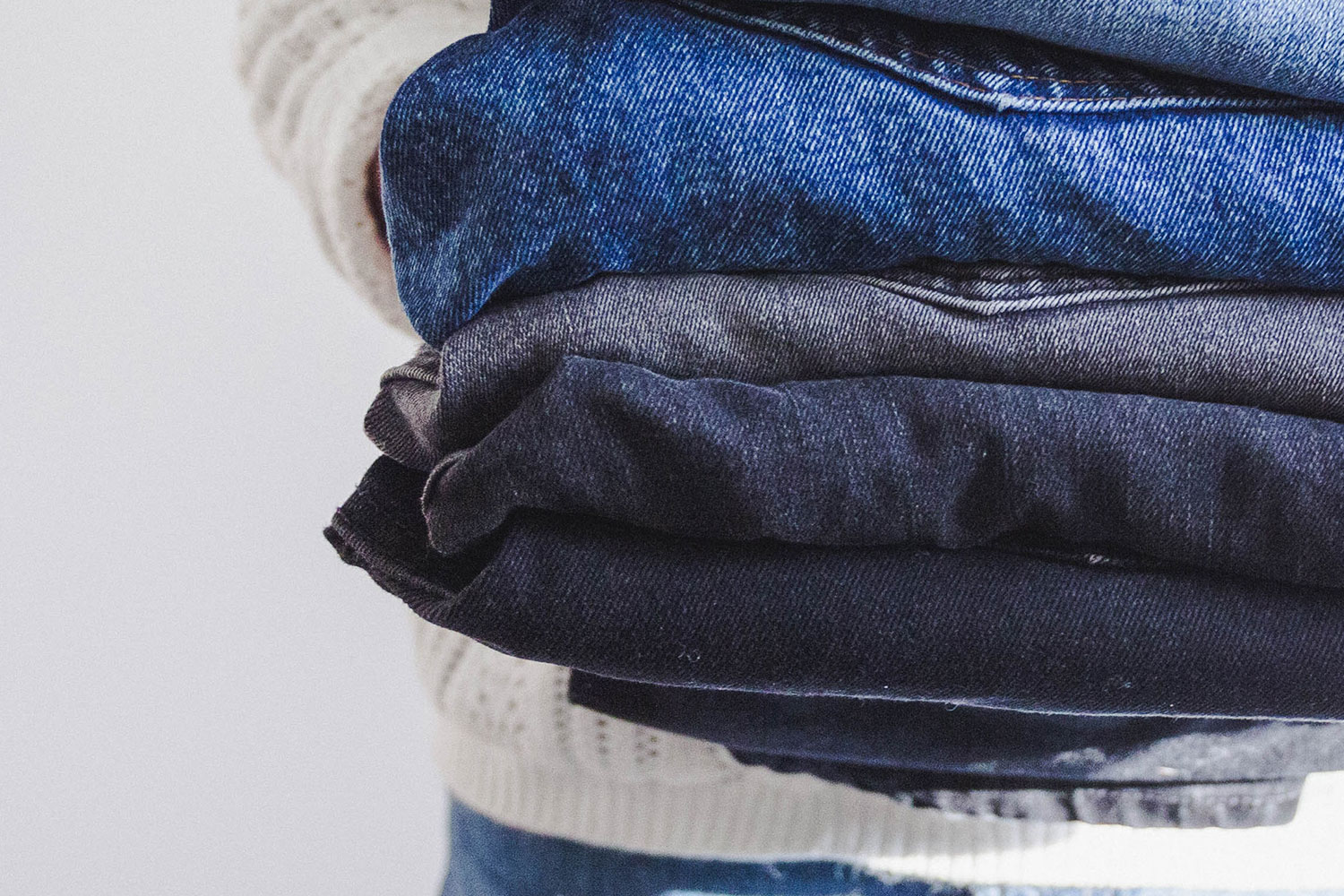 man holding a pile of jeans