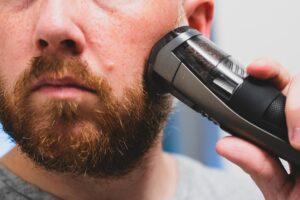 man holding beard trimmer against cheek