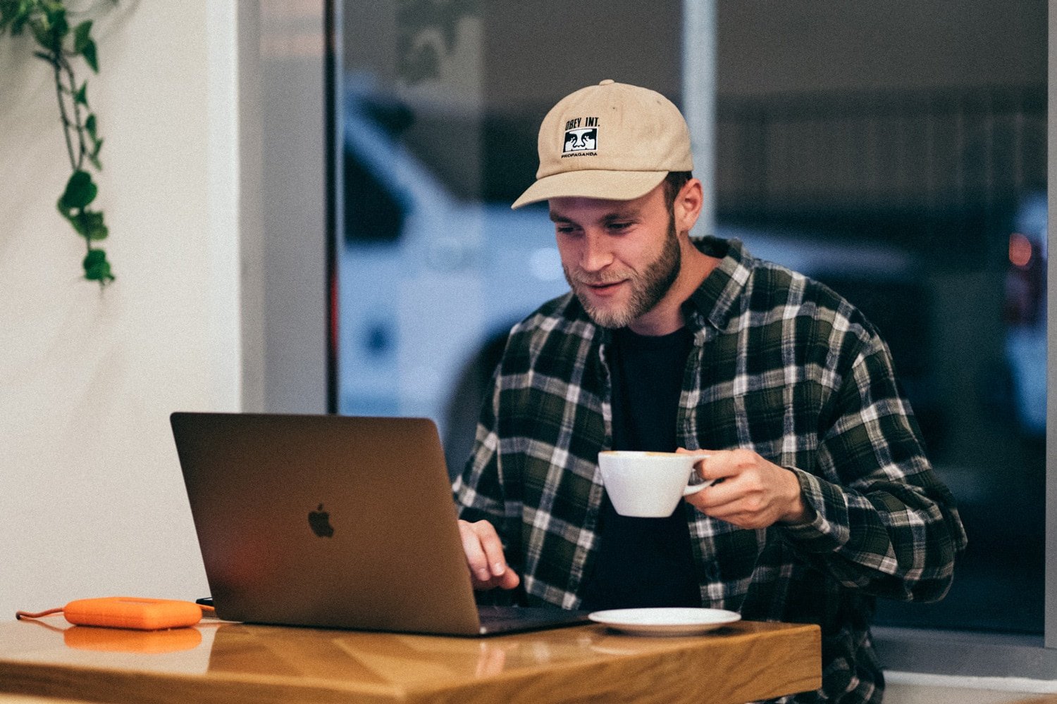 man holding cup of coffee on laptop
