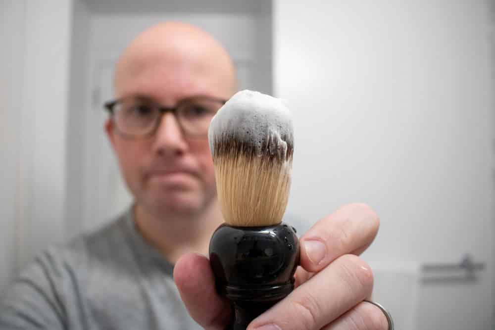 man holding shaving brush loaded with ghost town barber shave soap