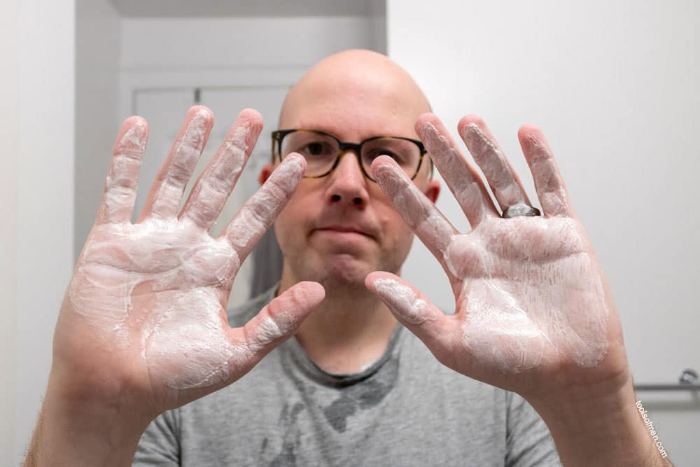 man holding up two hands thinly coated with shaving cream