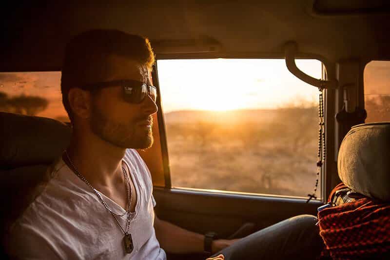 man in car drying with sunset in background