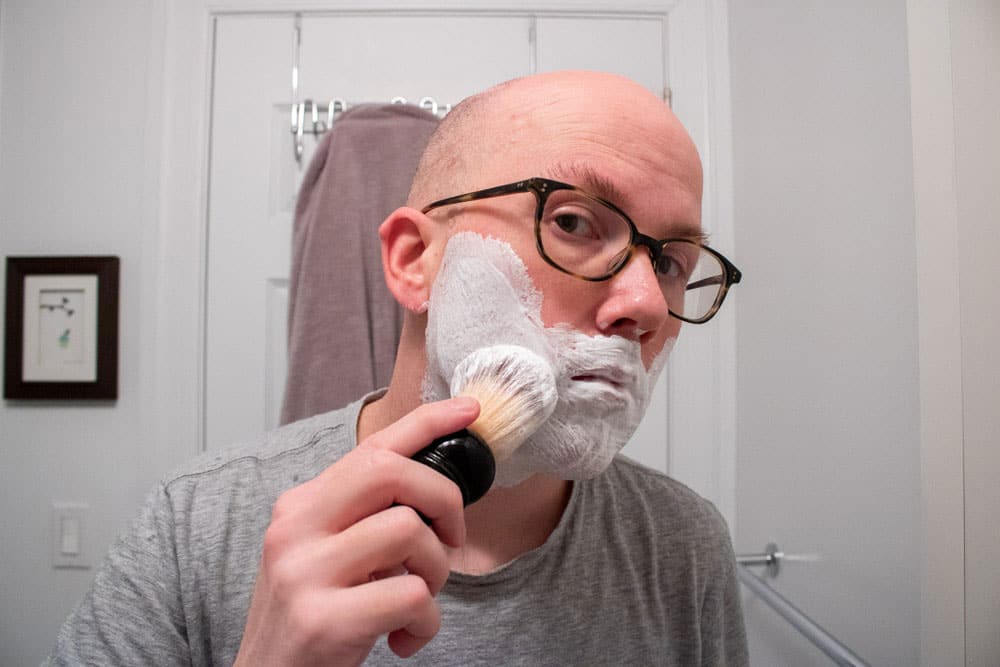 man lathering face with shaving brush