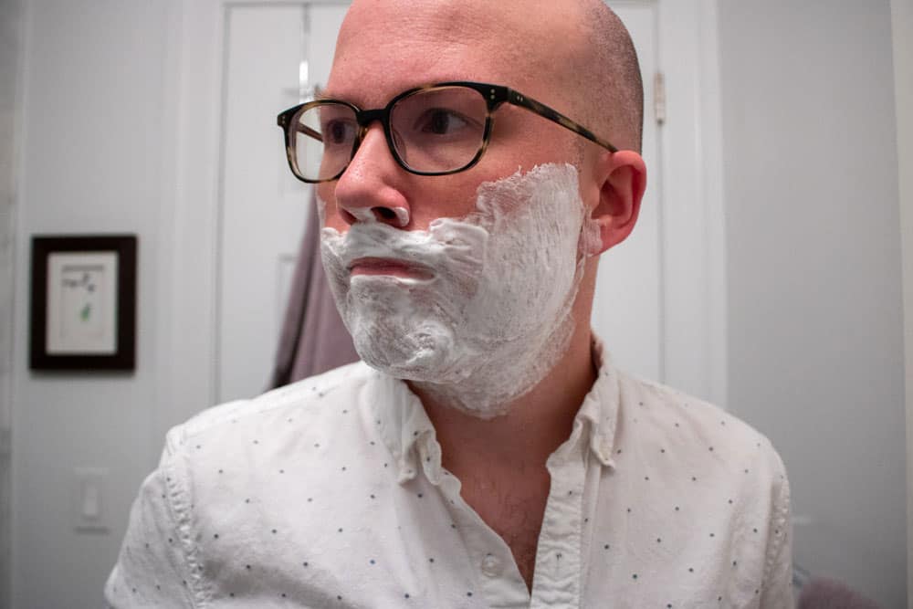 man looking to side with shaving cream applied to face