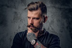 man looking to the side with hand up to beard