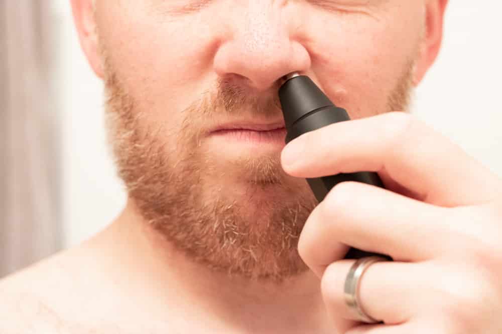 man putting manscaped weed whacker up nose