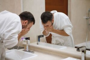 man rinsing off face over sink