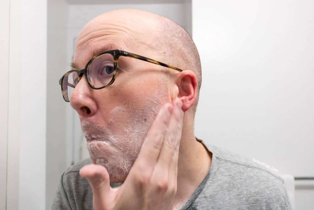 man rubbing a thin coat of shaving cream to face