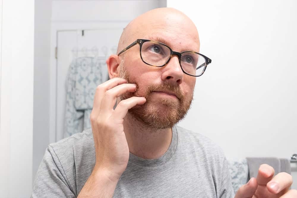 man rubbing beard with fingertips