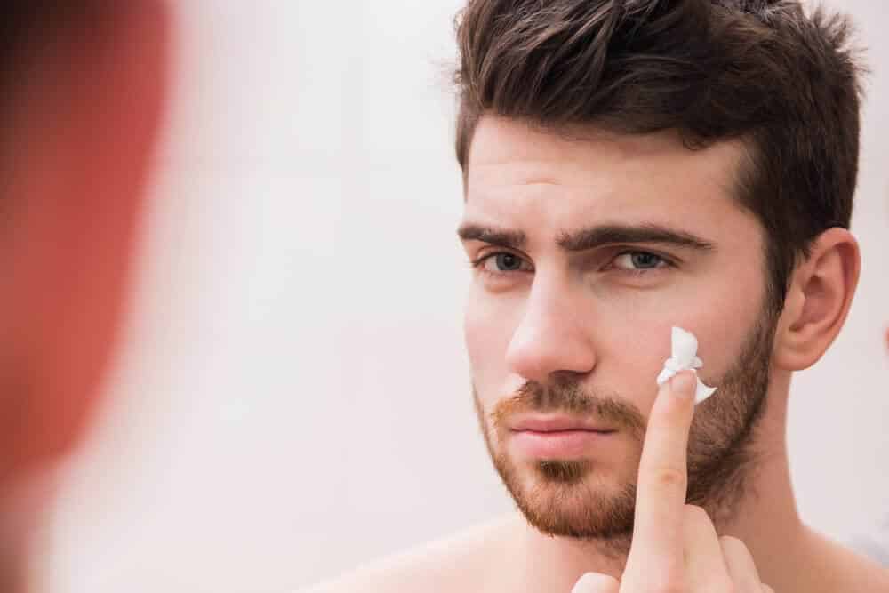man rubbing cream on face