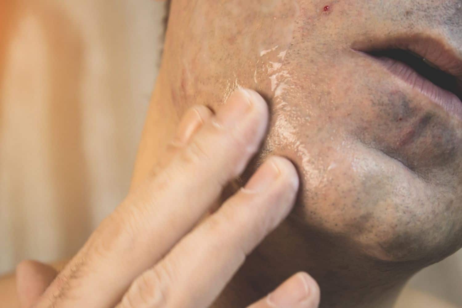 man rubbing pre shave oil on face