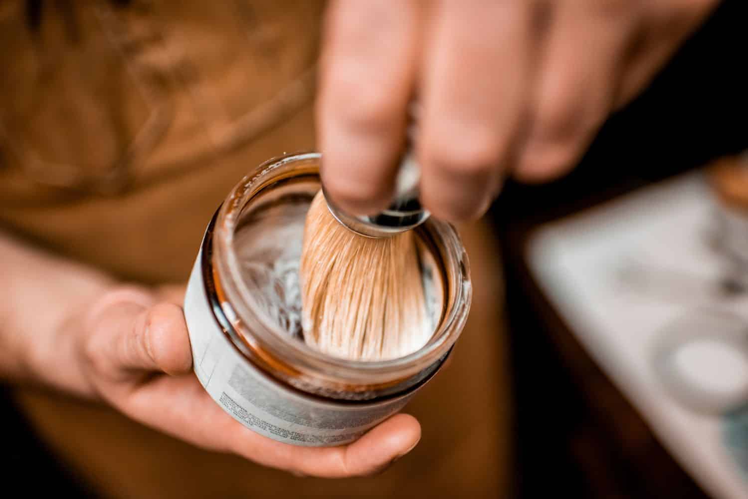 man rubbing shaving brush in a bowl of shaving soap
