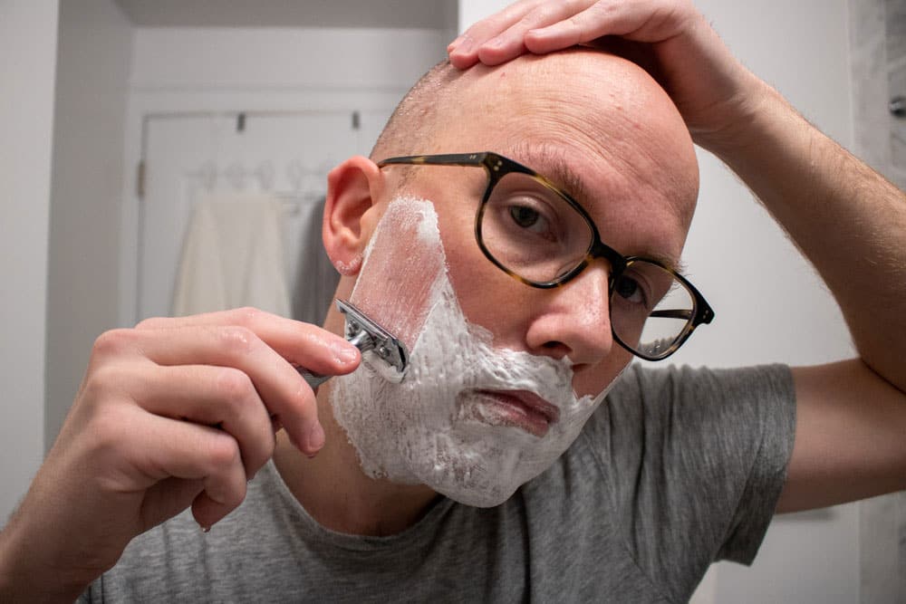 man shaving a safety razor to test body shop shaving cream 2