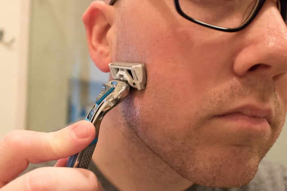 man shaving cheek with dollar shave club razor