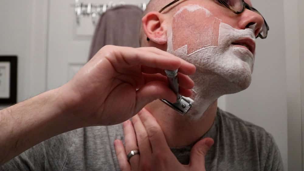 man shaving neck with safety razor