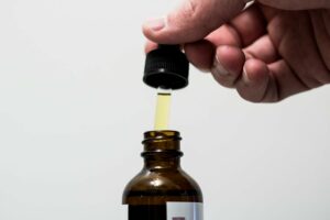 man taking a dropper out of a beard oil bottle