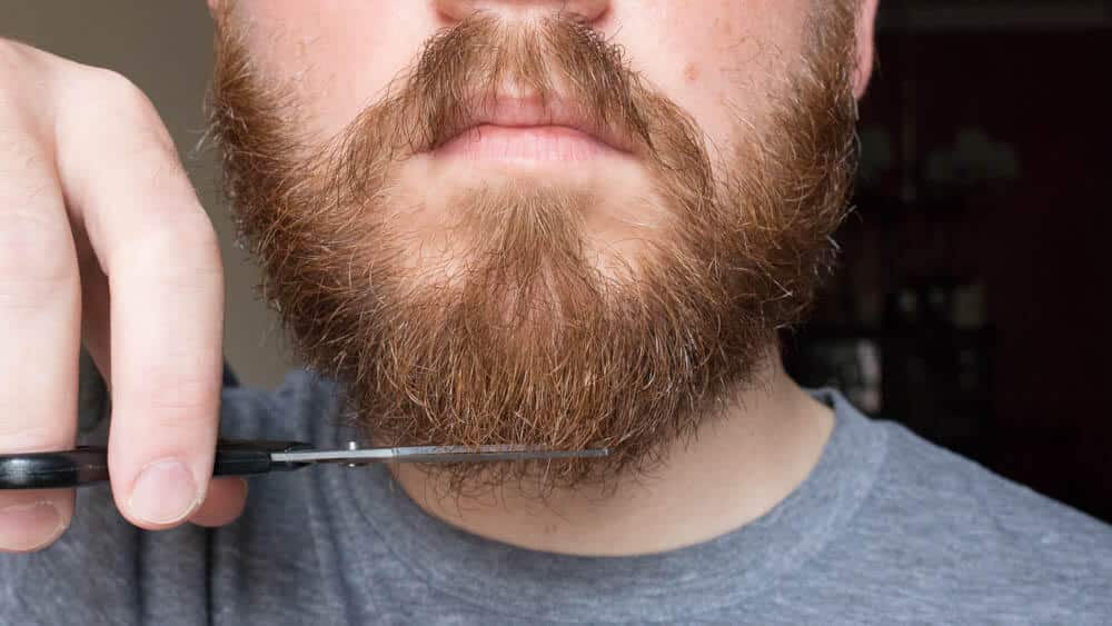 man trimming facial hair on chin