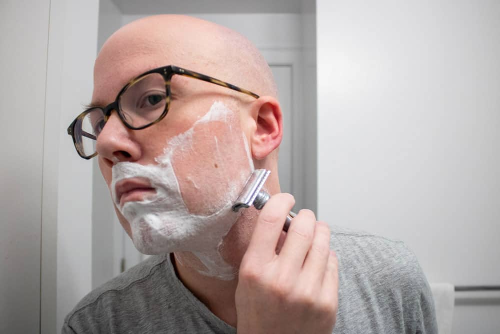 man using safety razor to shave