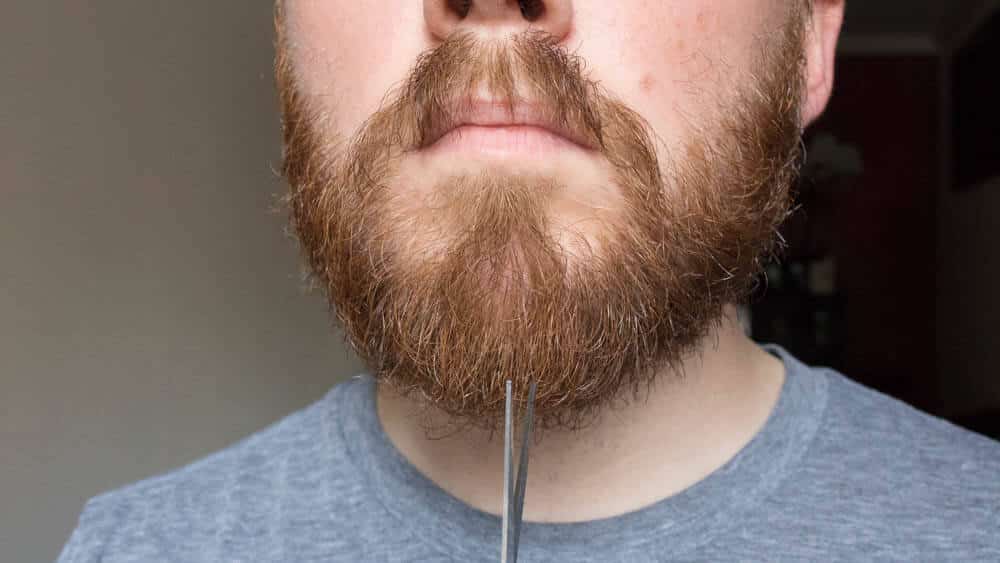 man using shears on chin to trim hair