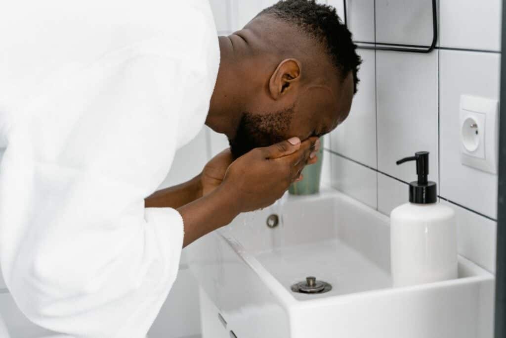 man washing his face over sink